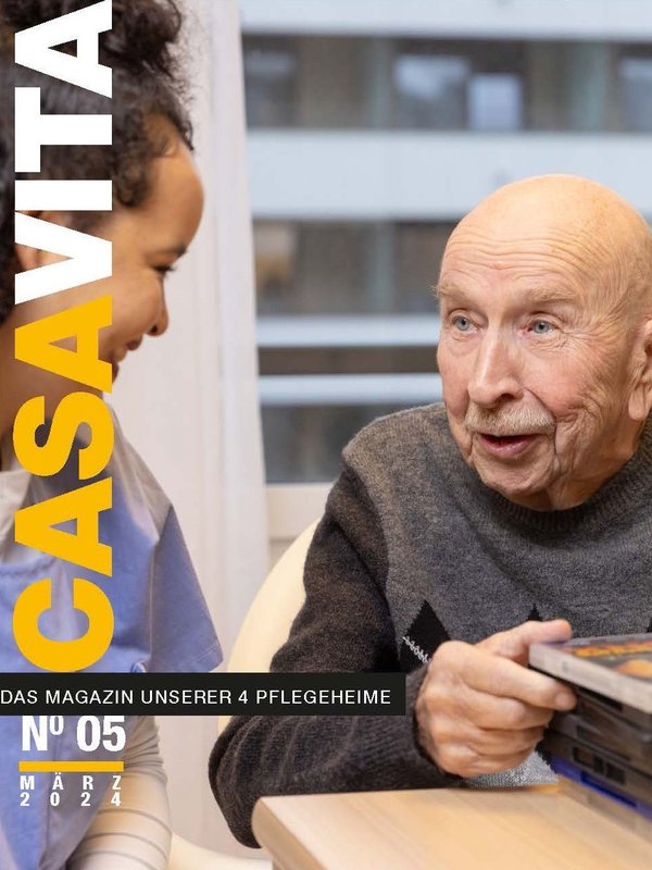 Titelbild der fünften Ausgabe des Casavita Magazins: Ein Bewohnender geht durch eine Beige aufeinandergestapelte DVD's und redet über diese mit einer Pflegeperson welche ihn anlächelt.